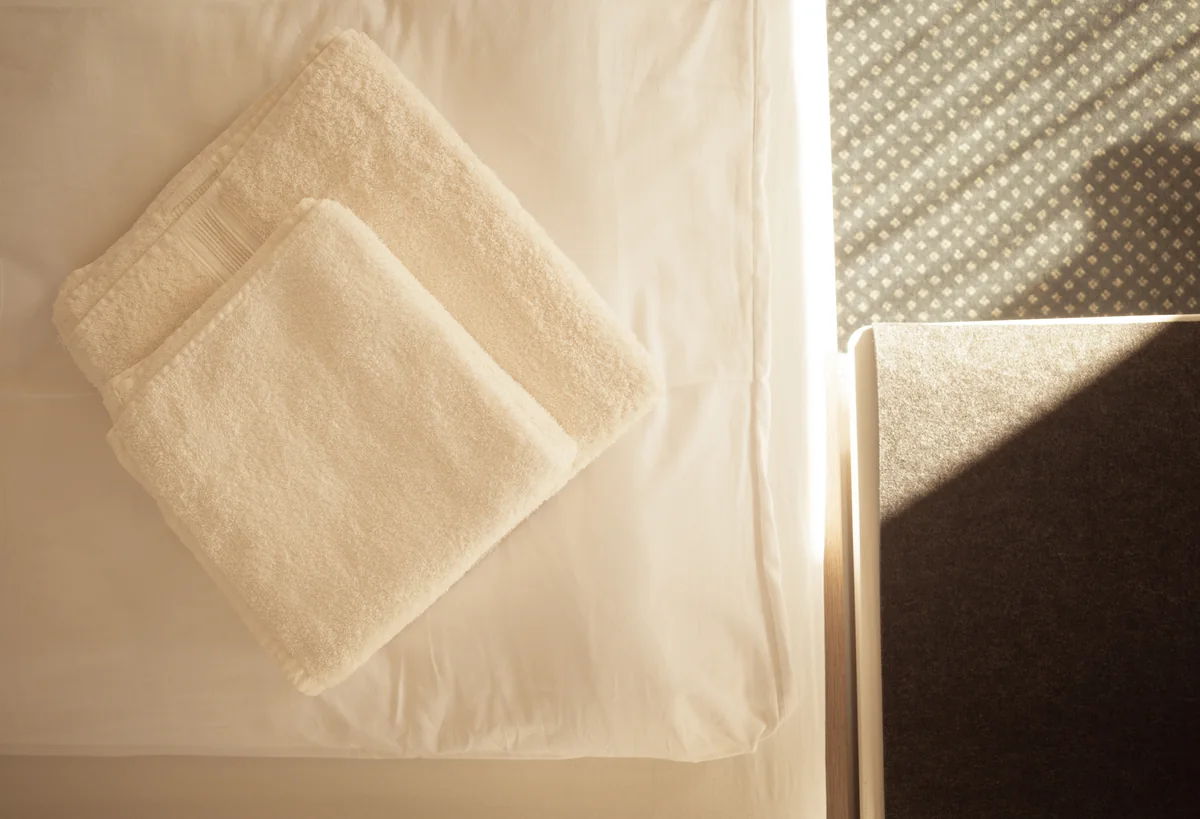 Frisch gefaltete Handtücher auf dem Bett im Sonnenlicht