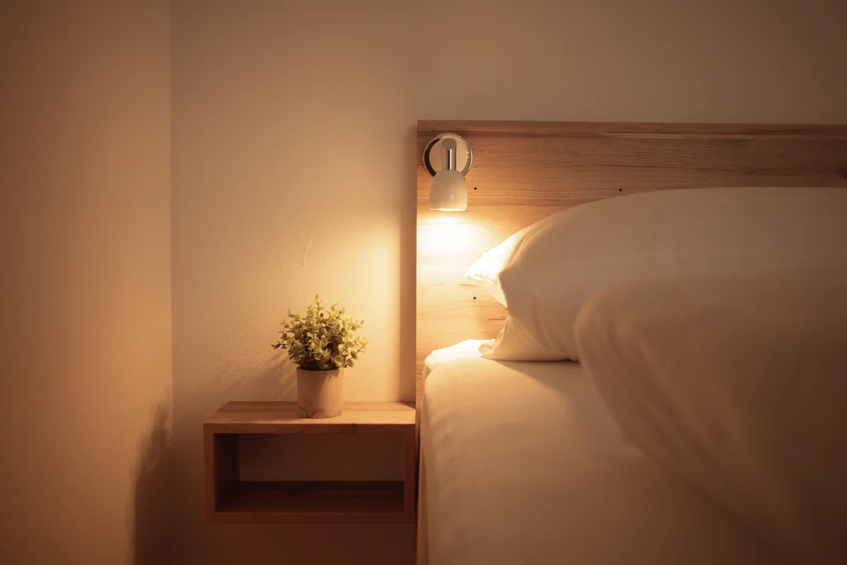Warmes Licht am Nachttisch und Doppelbett im Komfortzimmer Plus