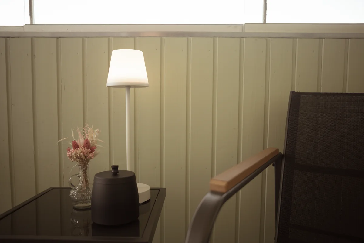Sessel und kleiner Tisch mit Blumen auf dem verglasten Balkon