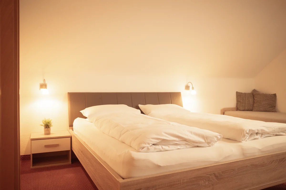 Doppelbett mit Nachttischen und warmen Leselampen im Doppelzimmer