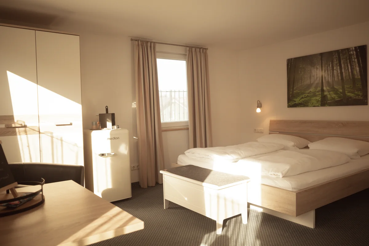 Komfortzimmer mit Doppelbett, Küchenzeile und Sitzecke im Sonnenlicht