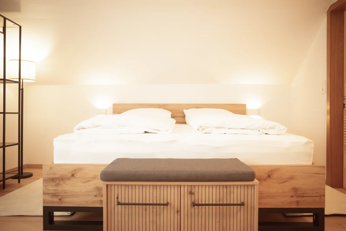 Doppelbett mit Holzrahmen und Bank im Doppelzimmer mit Balkon