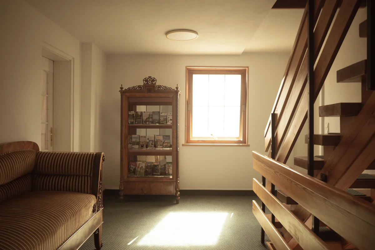 Sitzplatz und Vitrine neben der Holztreppe im Eingangsbereich der Pension