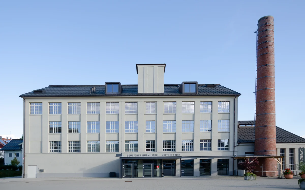 Deutsches Hutmuseum in Lindenberg mit heller Fassade und historischem Backsteinschornstein
