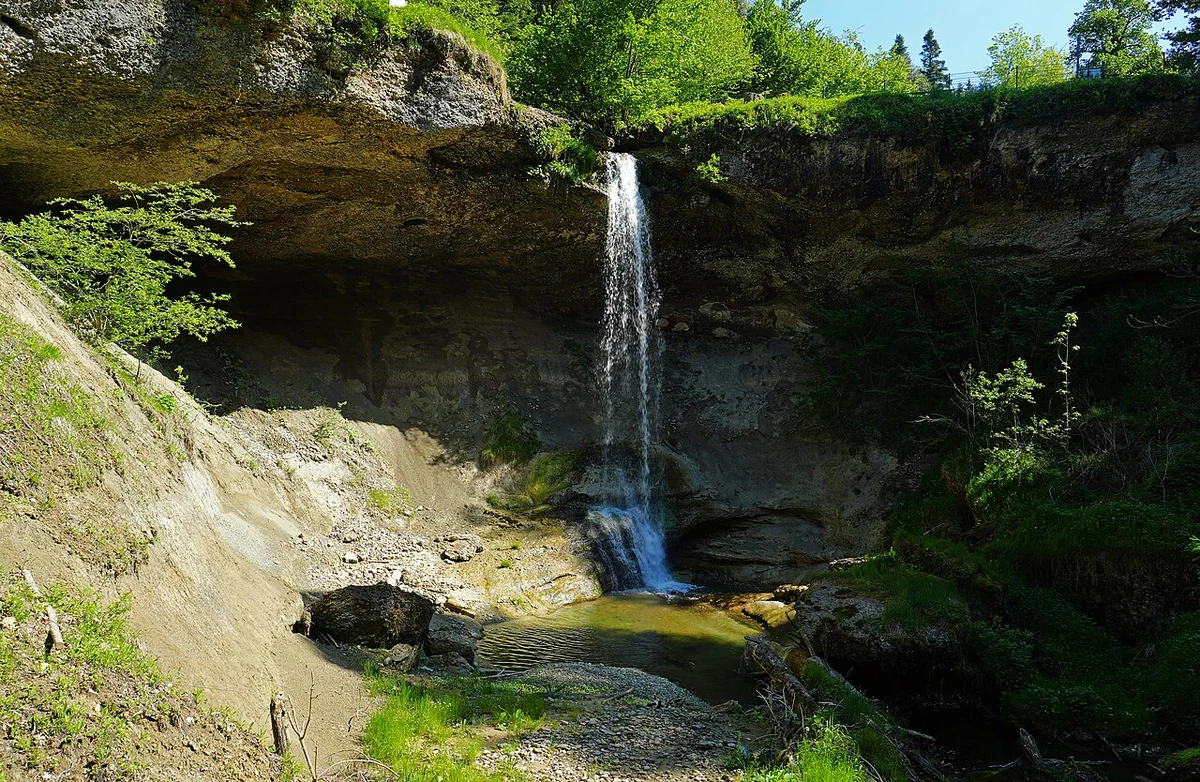 Scheidegger Wasserfall zwischen bewachsenen Felsen und grünen Bäumen